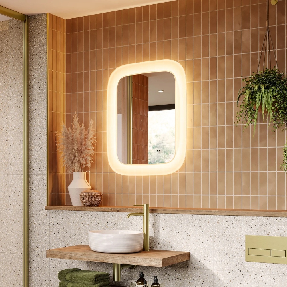 Lifestyle image of the hib. Cassini Curve 600mm x 800mm Deep Border LED Mirror mounted on a brown tiled bathroom wall above a round countertop basin